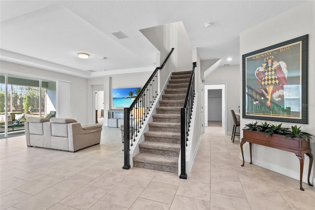 stairway featuring a textured ceiling and tile patterned floors