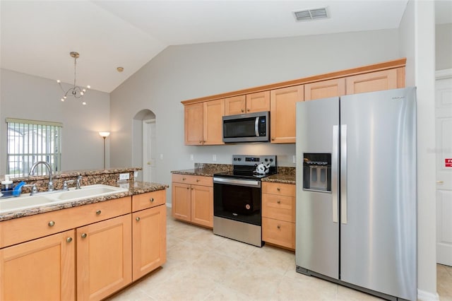 kitchen with light brown cabinets, stainless steel appliances, sink, a notable chandelier, and vaulted ceiling