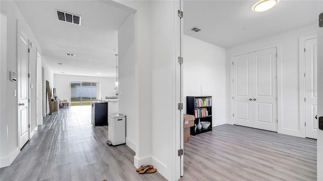 hallway with a textured ceiling and light wood-type flooring