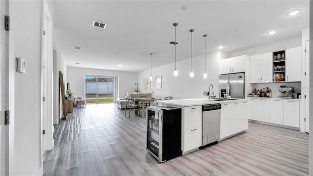 kitchen with white cabinetry, an island with sink, stainless steel appliances, wine cooler, and hanging light fixtures