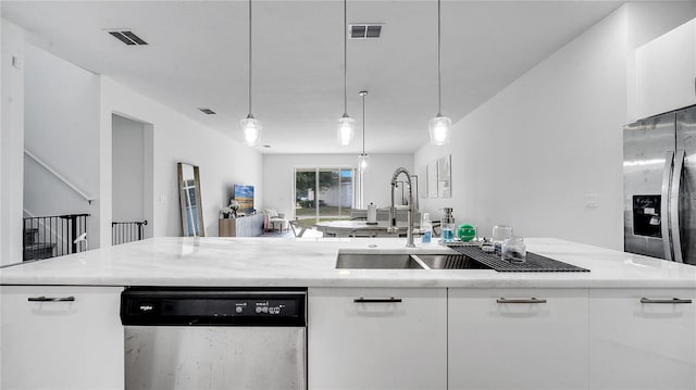 kitchen with appliances with stainless steel finishes, white cabinetry, hanging light fixtures, and sink