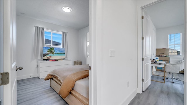 bedroom with light hardwood / wood-style floors and a textured ceiling