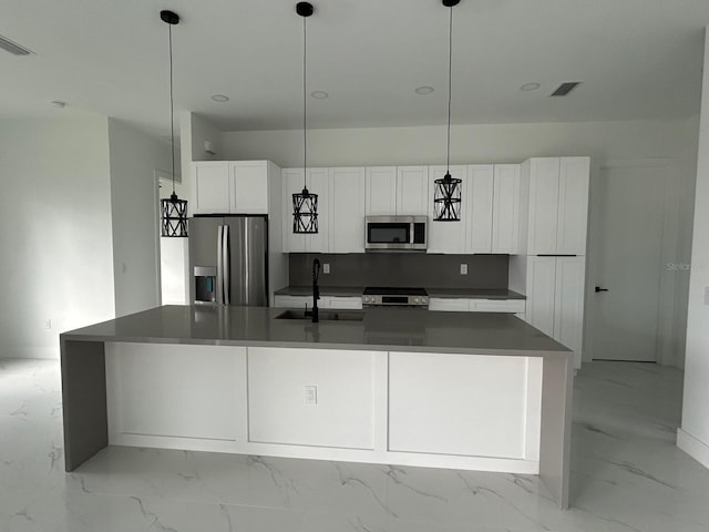 kitchen with white cabinetry, an island with sink, appliances with stainless steel finishes, decorative light fixtures, and sink