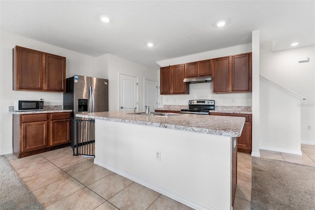 kitchen with stainless steel appliances, sink, a kitchen island with sink, and light tile patterned floors