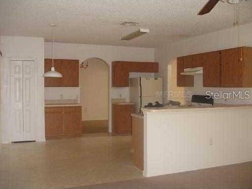 kitchen with decorative light fixtures, ceiling fan, white refrigerator, and a textured ceiling