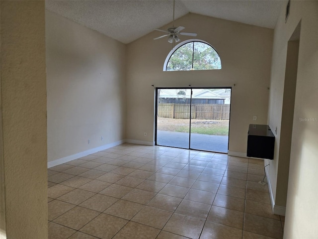 empty room with ceiling fan, a textured ceiling, light tile patterned floors, and high vaulted ceiling