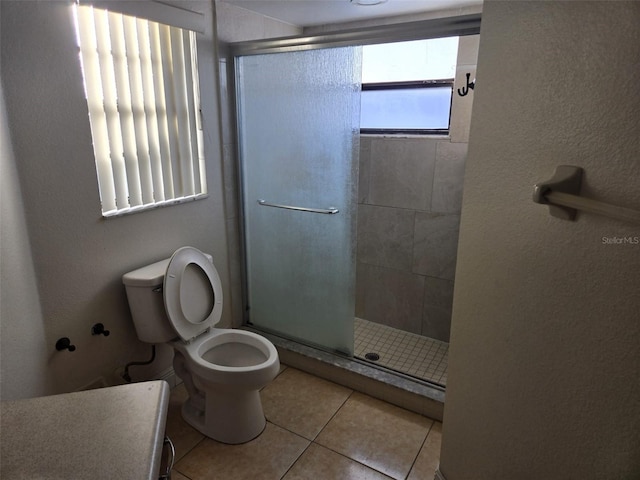 bathroom featuring a shower with shower door, tile patterned flooring, and toilet