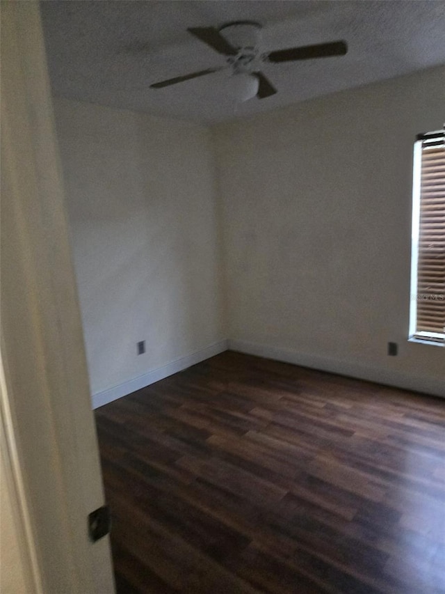 empty room featuring ceiling fan and dark wood-type flooring