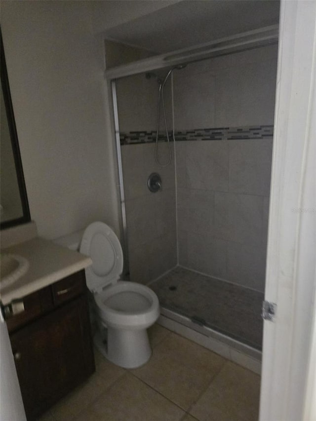 bathroom with walk in shower, vanity, tile patterned floors, and toilet