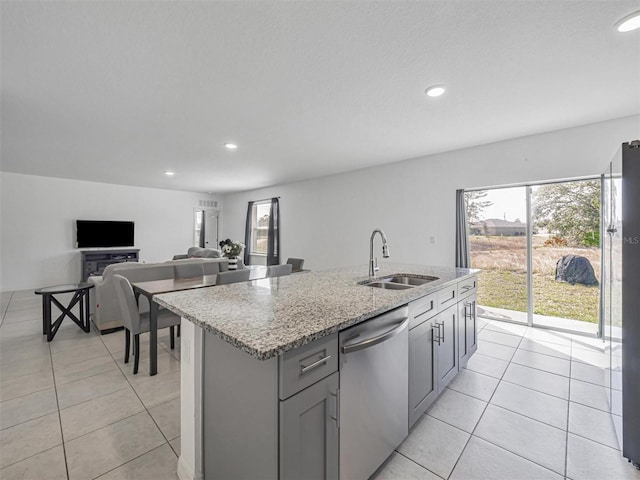 kitchen featuring a center island with sink, gray cabinets, stainless steel appliances, light stone counters, and sink