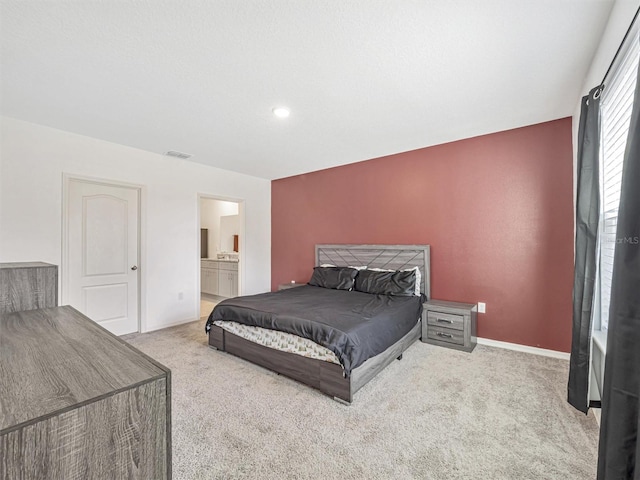 bedroom with light colored carpet and connected bathroom