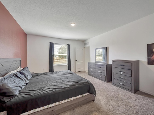 bedroom featuring a textured ceiling and light colored carpet