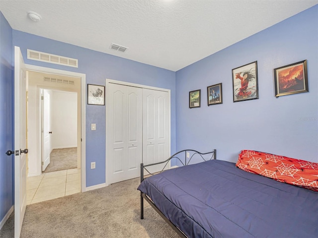 carpeted bedroom with a closet and a textured ceiling