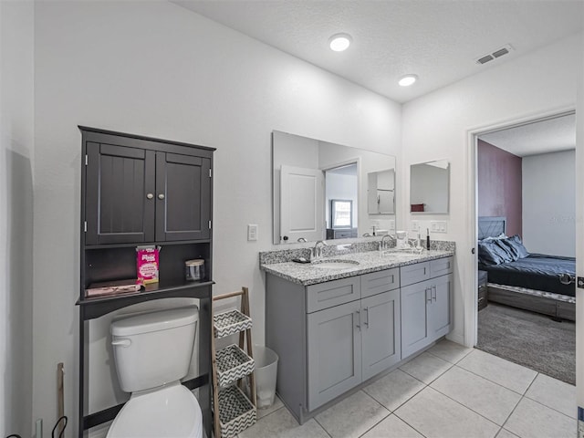 bathroom with a textured ceiling, toilet, vanity, and tile patterned flooring