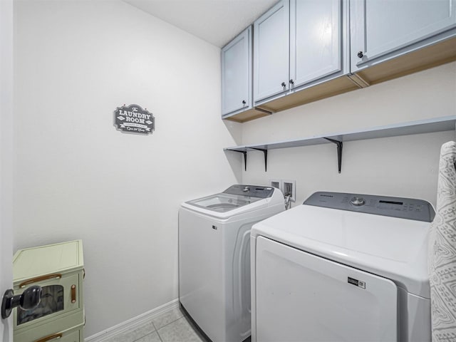 laundry area featuring washing machine and dryer, cabinets, and light tile patterned flooring