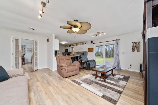 living room featuring light wood-type flooring, french doors, a textured ceiling, and ceiling fan