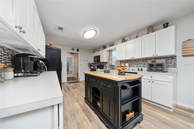 kitchen featuring backsplash, white cabinetry, black appliances, and light wood-type flooring