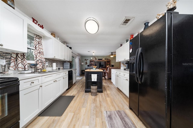 kitchen featuring black appliances, white cabinets, decorative backsplash, and light wood-type flooring