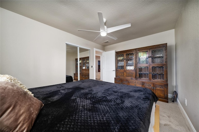 bedroom with ceiling fan, a closet, light carpet, and a textured ceiling