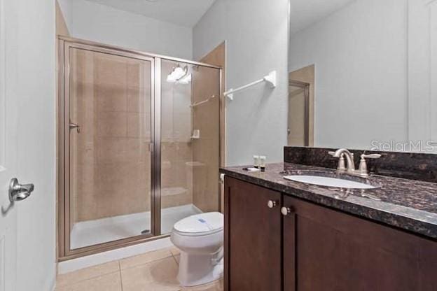 bathroom with toilet, vanity, tile patterned floors, and a shower with shower door