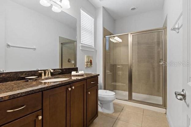 bathroom with vanity, walk in shower, tile patterned floors, and toilet