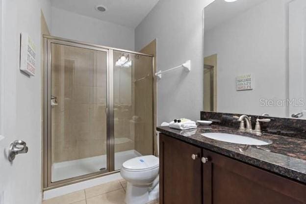 bathroom with tile patterned floors, toilet, a shower with door, and vanity