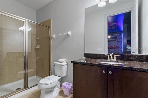 bathroom featuring an enclosed shower, vanity, tile patterned flooring, and toilet