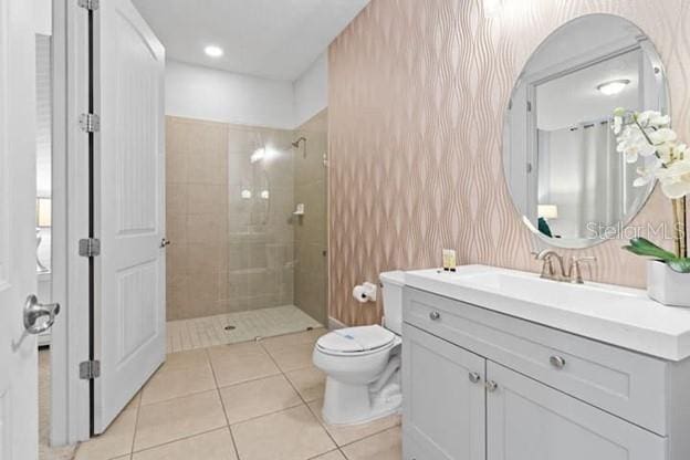 bathroom featuring vanity, tile patterned floors, toilet, and tiled shower