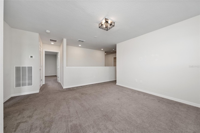 carpeted empty room featuring a textured ceiling