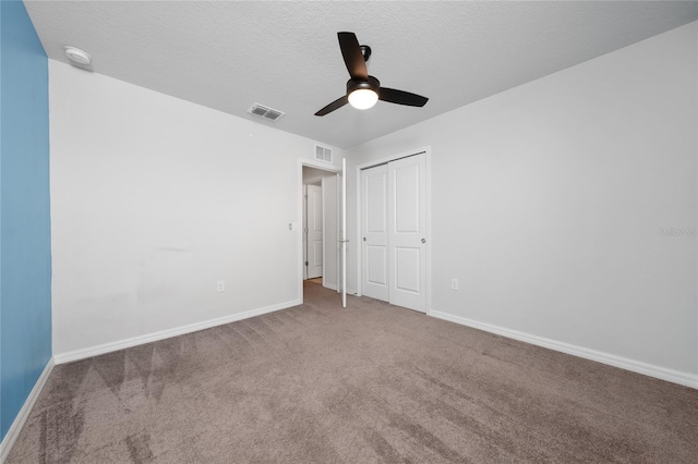 unfurnished bedroom featuring ceiling fan, a textured ceiling, a closet, and carpet floors