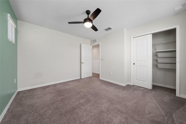 unfurnished bedroom featuring ceiling fan, a closet, and dark carpet