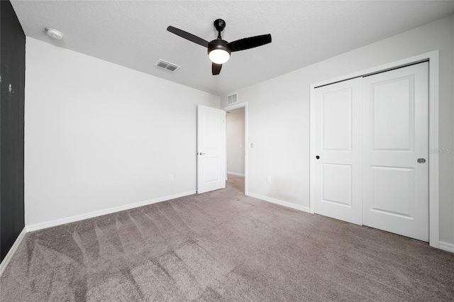 unfurnished bedroom featuring ceiling fan, a closet, carpet, and a textured ceiling