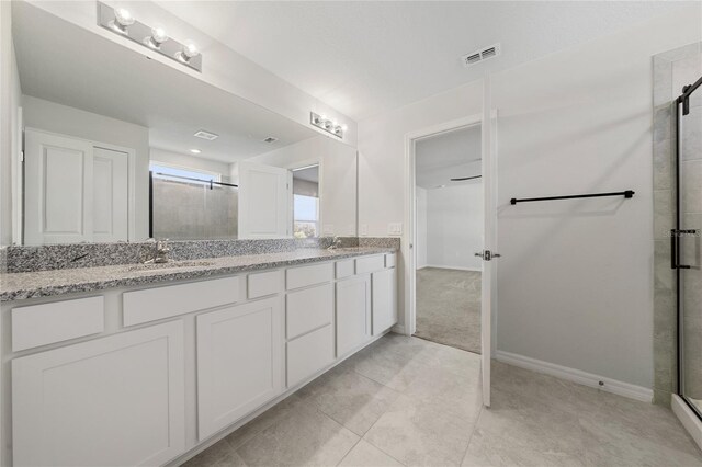 bathroom with a shower with shower door, tile patterned floors, and vanity