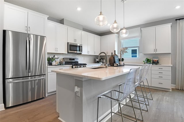 kitchen with a kitchen island with sink, sink, stainless steel appliances, and white cabinetry