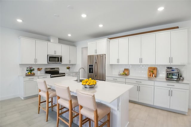 9093 Players Dr, Weeki Wachee, FL 34613 - kitchen with appliances with stainless steel finishes, a kitchen island with sink, a breakfast bar area, backsplash, and a sink