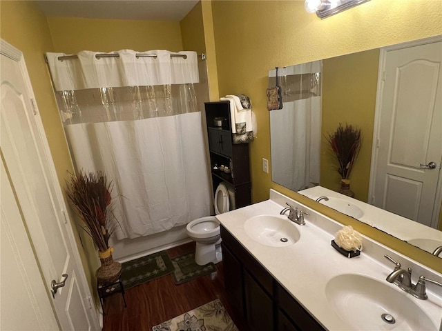 full bathroom featuring shower / bath combination with curtain, hardwood / wood-style flooring, vanity, stacked washer / drying machine, and toilet