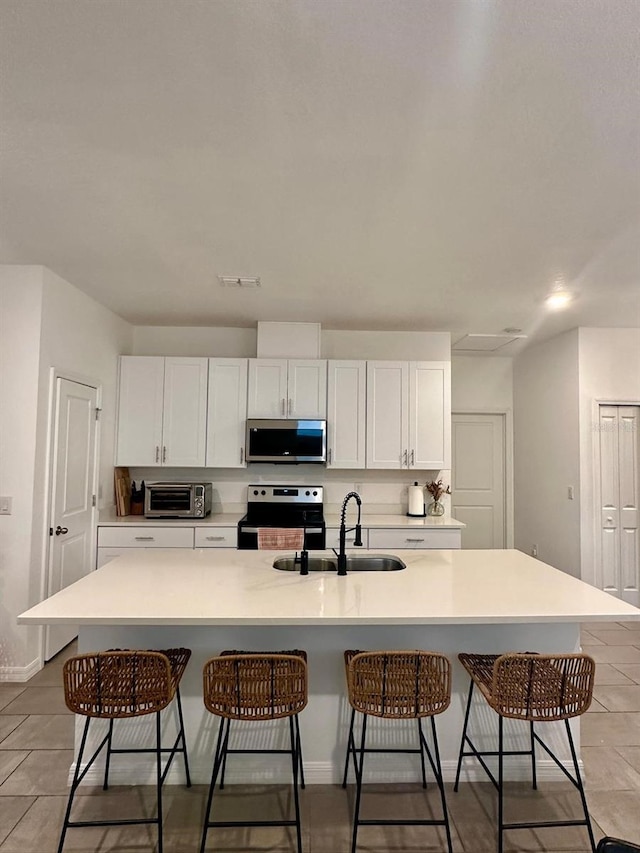 kitchen with white cabinetry, appliances with stainless steel finishes, and a center island with sink