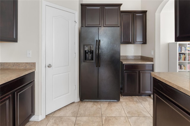 kitchen with light tile patterned floors, black fridge with ice dispenser, and dark brown cabinetry