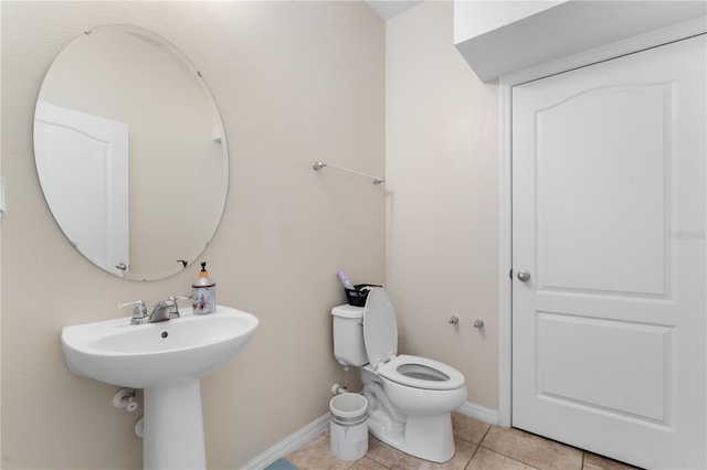 bathroom with toilet, tile patterned flooring, and sink