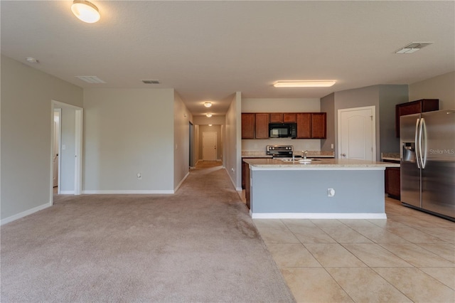 kitchen featuring a center island with sink, range with electric cooktop, stainless steel fridge, light tile patterned flooring, and sink