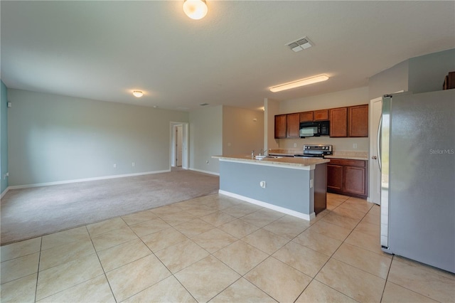 kitchen featuring light tile patterned flooring, appliances with stainless steel finishes, sink, and an island with sink