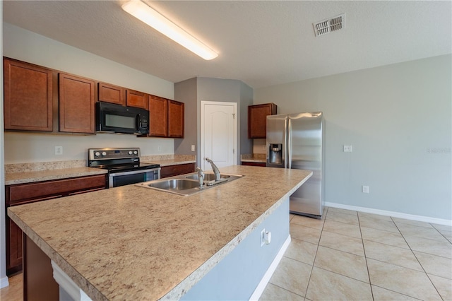 kitchen featuring light tile patterned floors, stainless steel appliances, sink, and a kitchen island with sink