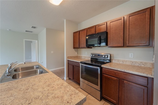 kitchen with sink, electric range, light tile patterned floors, and a textured ceiling