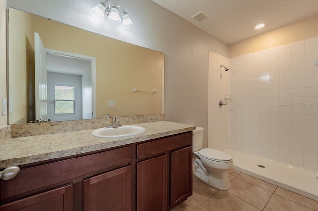 bathroom featuring tile patterned floors, toilet, vanity, and tiled shower