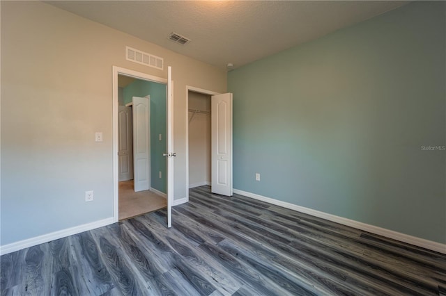 unfurnished bedroom with a closet, dark hardwood / wood-style floors, and a textured ceiling