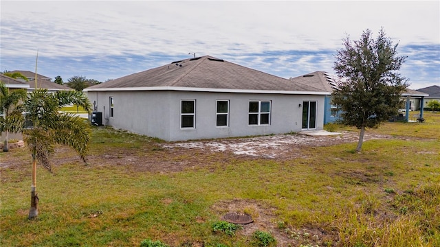 back of property with a lawn and central air condition unit