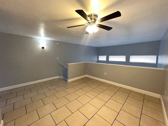 tiled spare room with ceiling fan