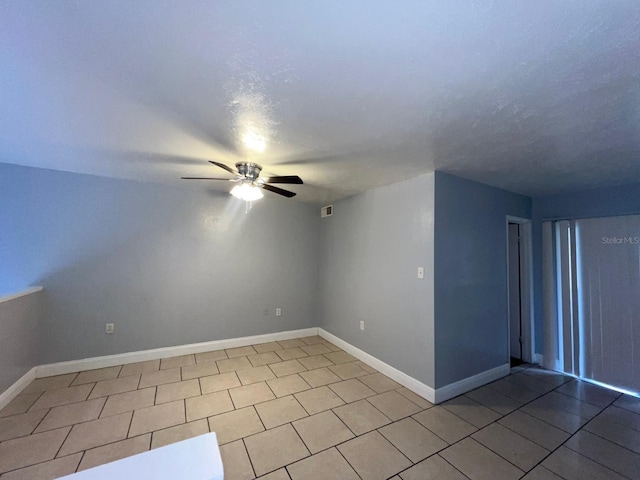 empty room featuring ceiling fan and light tile patterned floors