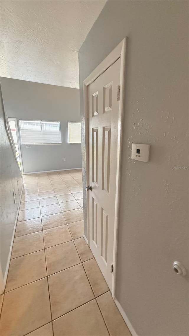 hallway with light tile patterned floors and a textured ceiling