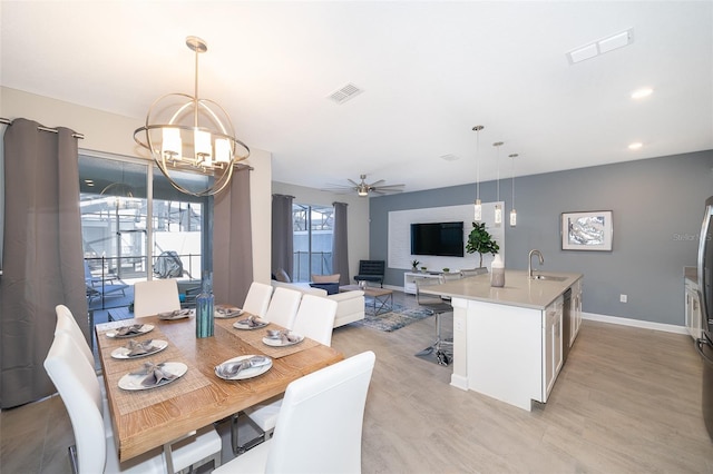 dining area with ceiling fan with notable chandelier and sink